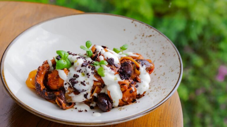 Handmade fettuccine with slow-cooked octopus, tomato sauce, olives, and capers served outdoors at Klive Beach Club